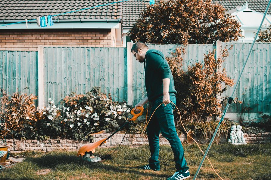 Man using an electric grass trimmer on a lawn, a weekend lawn-care service