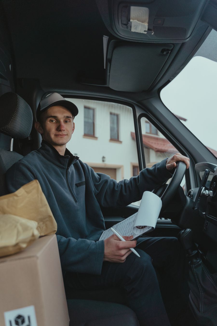 Delivery driver in the driver's seat of a van holding delivery paperwork