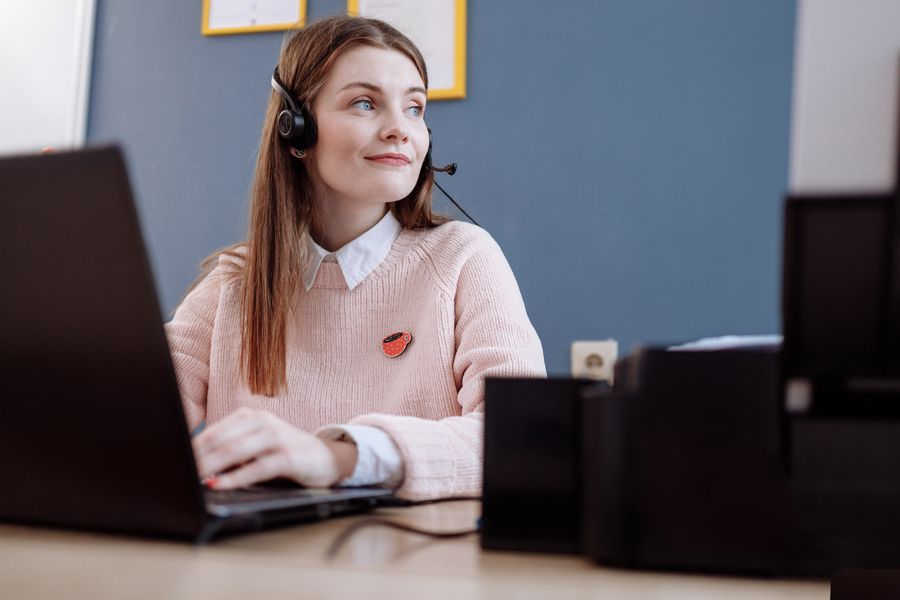 Woman wearing a headset while working on a laptop