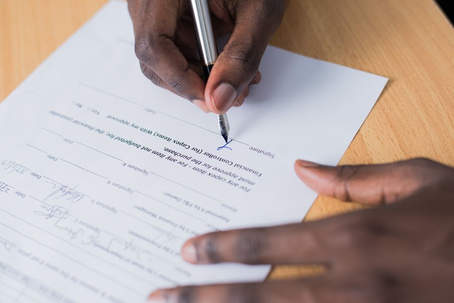Close-up of a hand signing a contract document with a pen