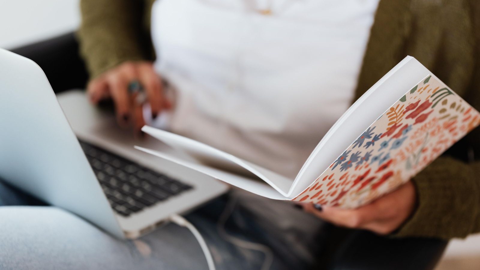 Woman working from home with a laptop on her lap, holding an open floral-patterned planner