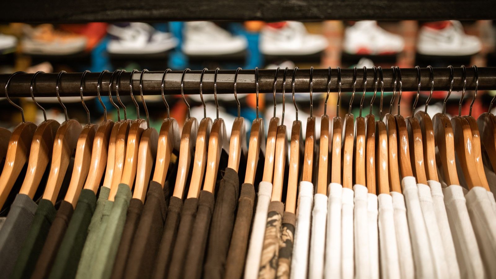Row of t-shirts on wooden hangers on a clothing rack
