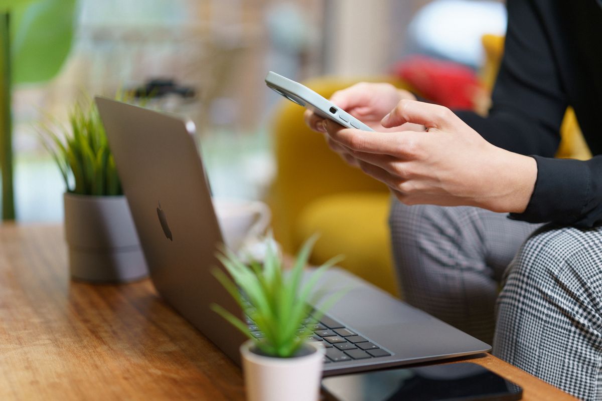 Person working on a smartphone and laptop at home