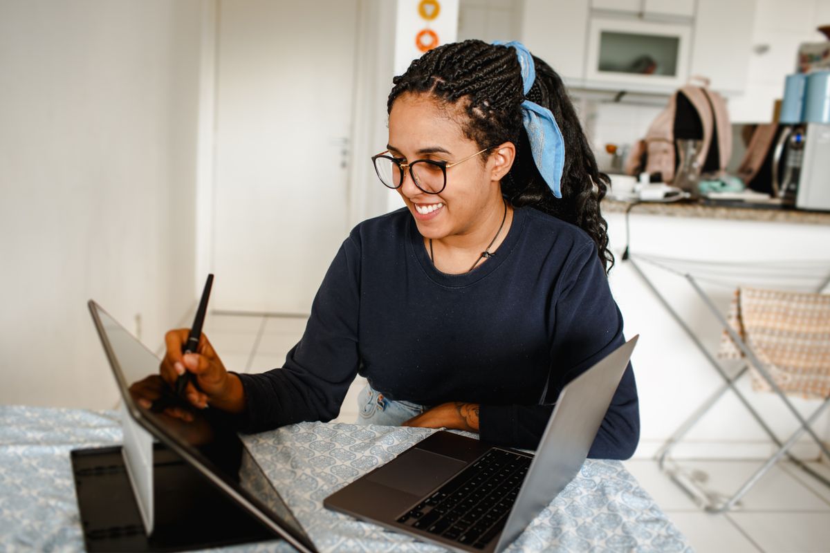 Woman using a tablet and laptop at home
