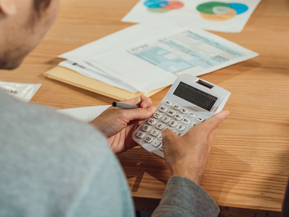 Person using a calculator at a desk with financial documents