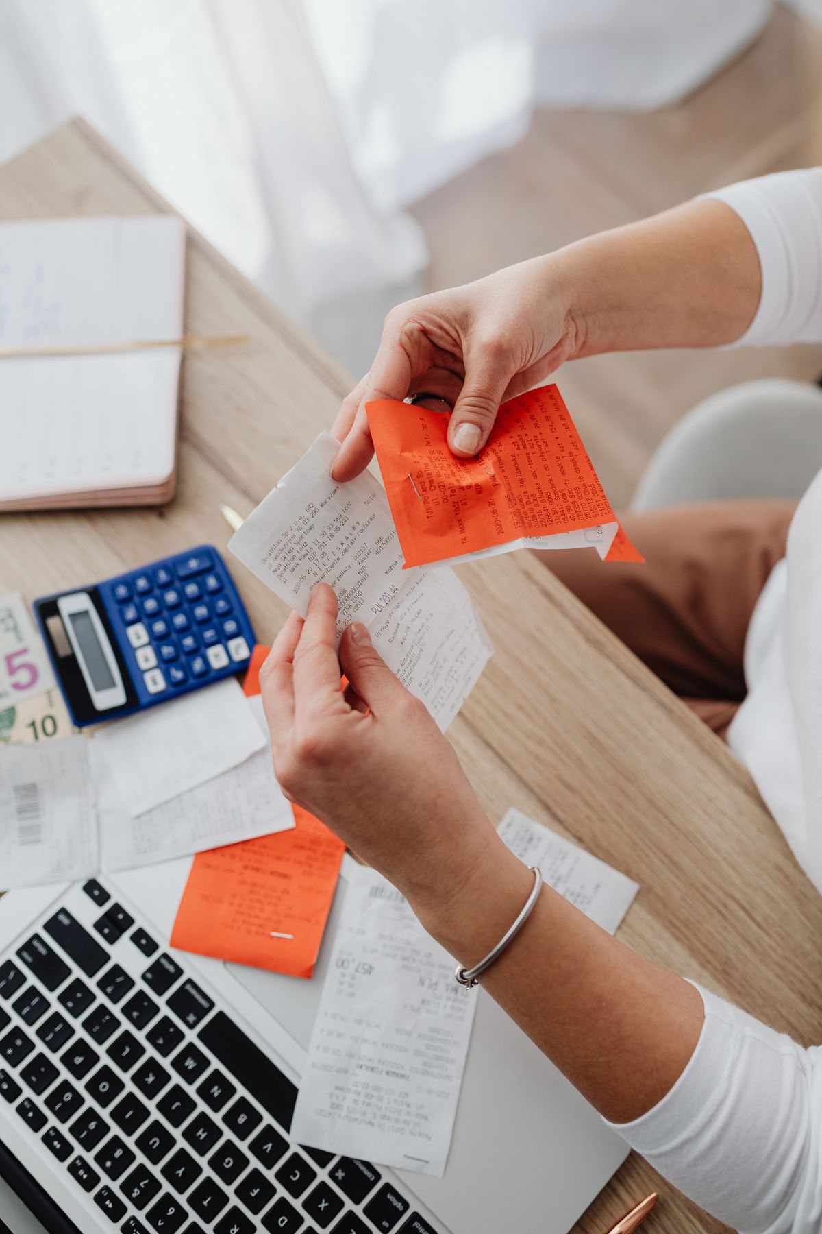 Top view of a person organizing finances with a calculator, receipts, and notes