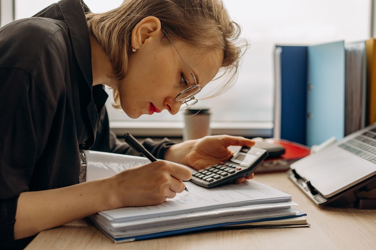Woman working on accounting with a calculator and documents
