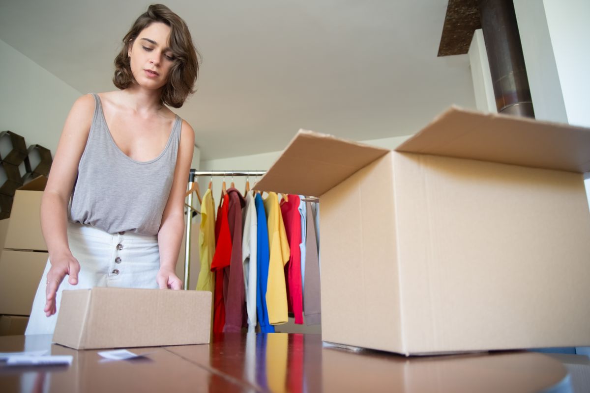 Woman packing clothing items into a cardboard box for an online order