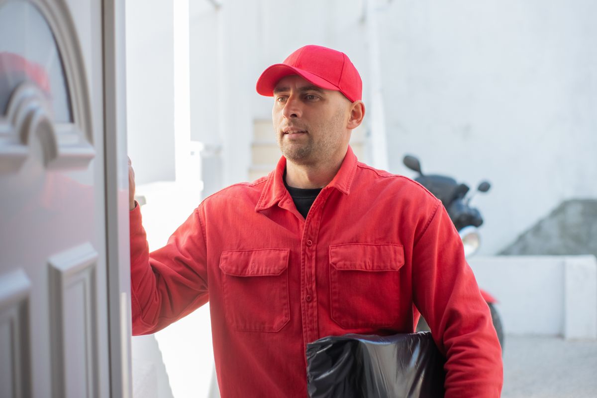 Delivery courier holding a parcel at a customer's front door